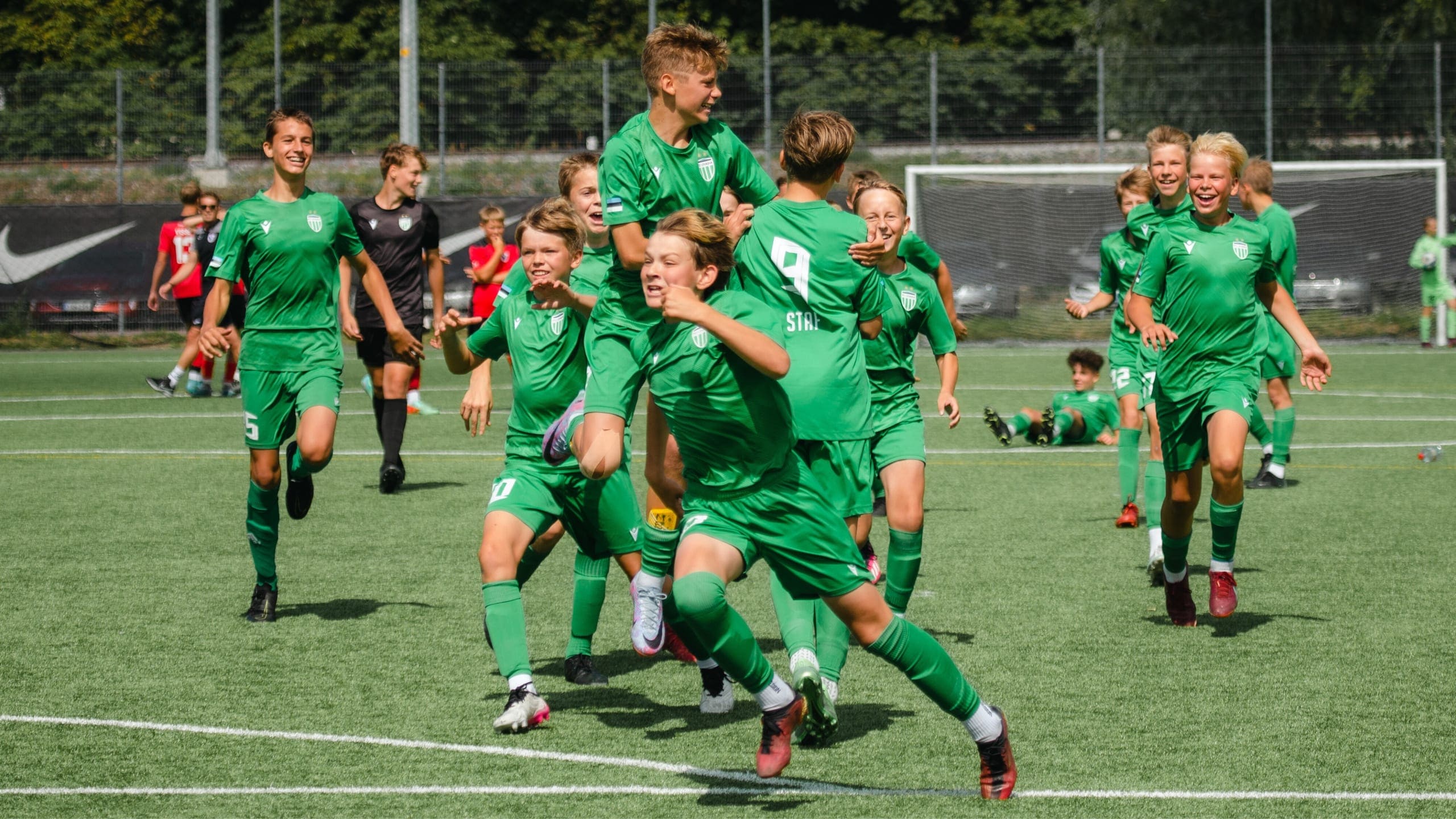 A squad in green running to celebrate a goal